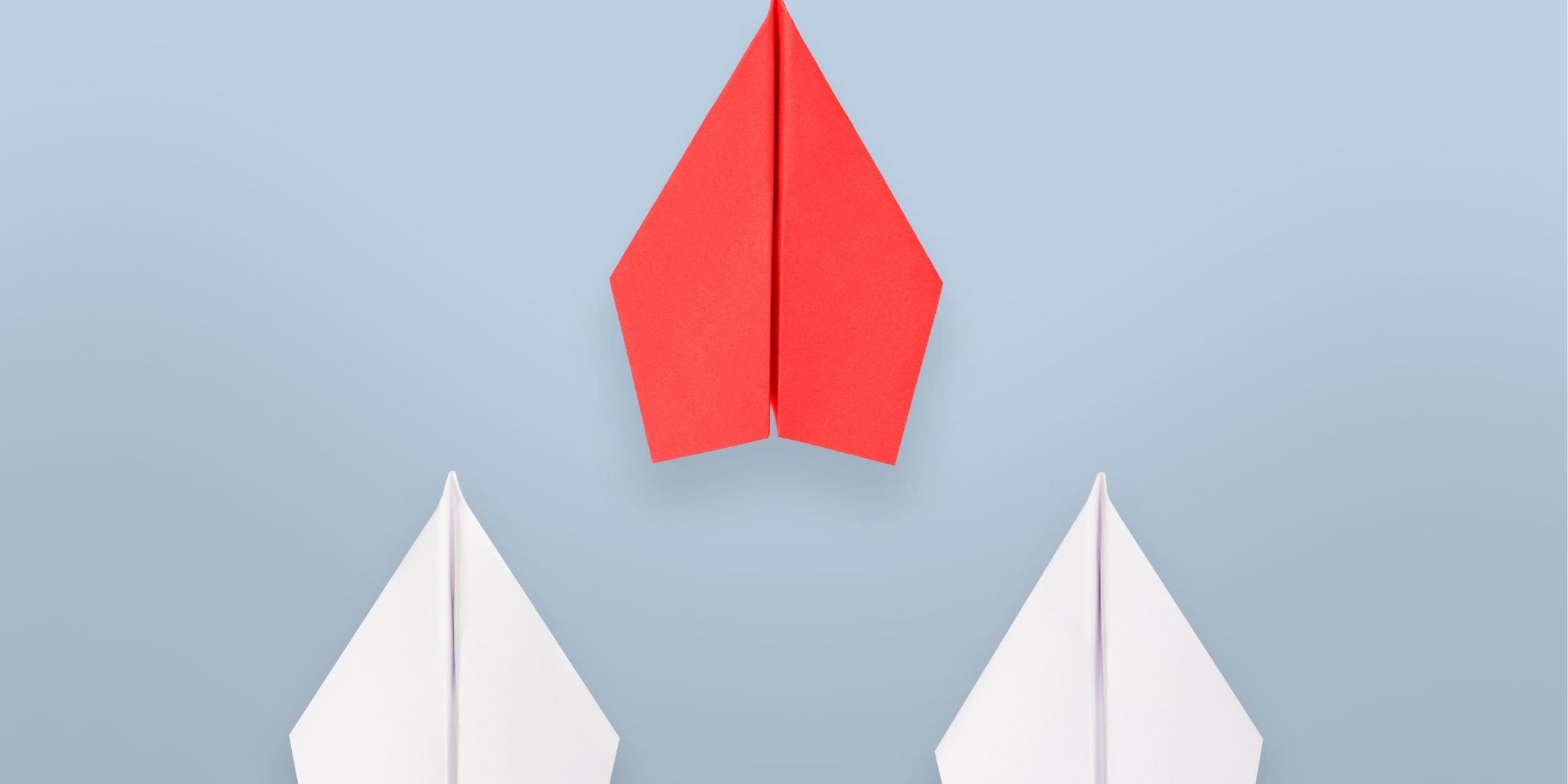 red airplane pictured ahead of two white airplanes