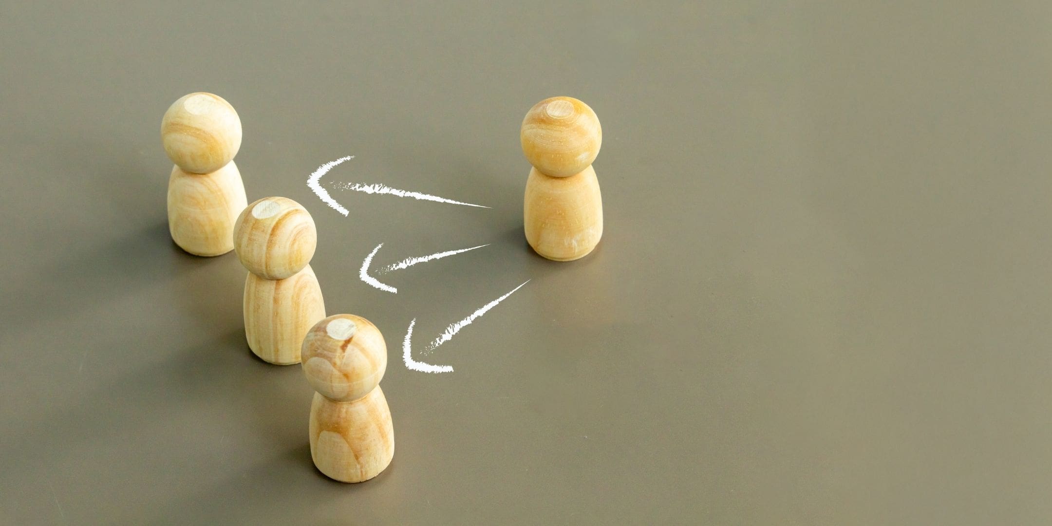one wooden peg figure facing 3 peg figures with arrows pointing from the singular peg to the 3 pegs symbolizing power dynamic
