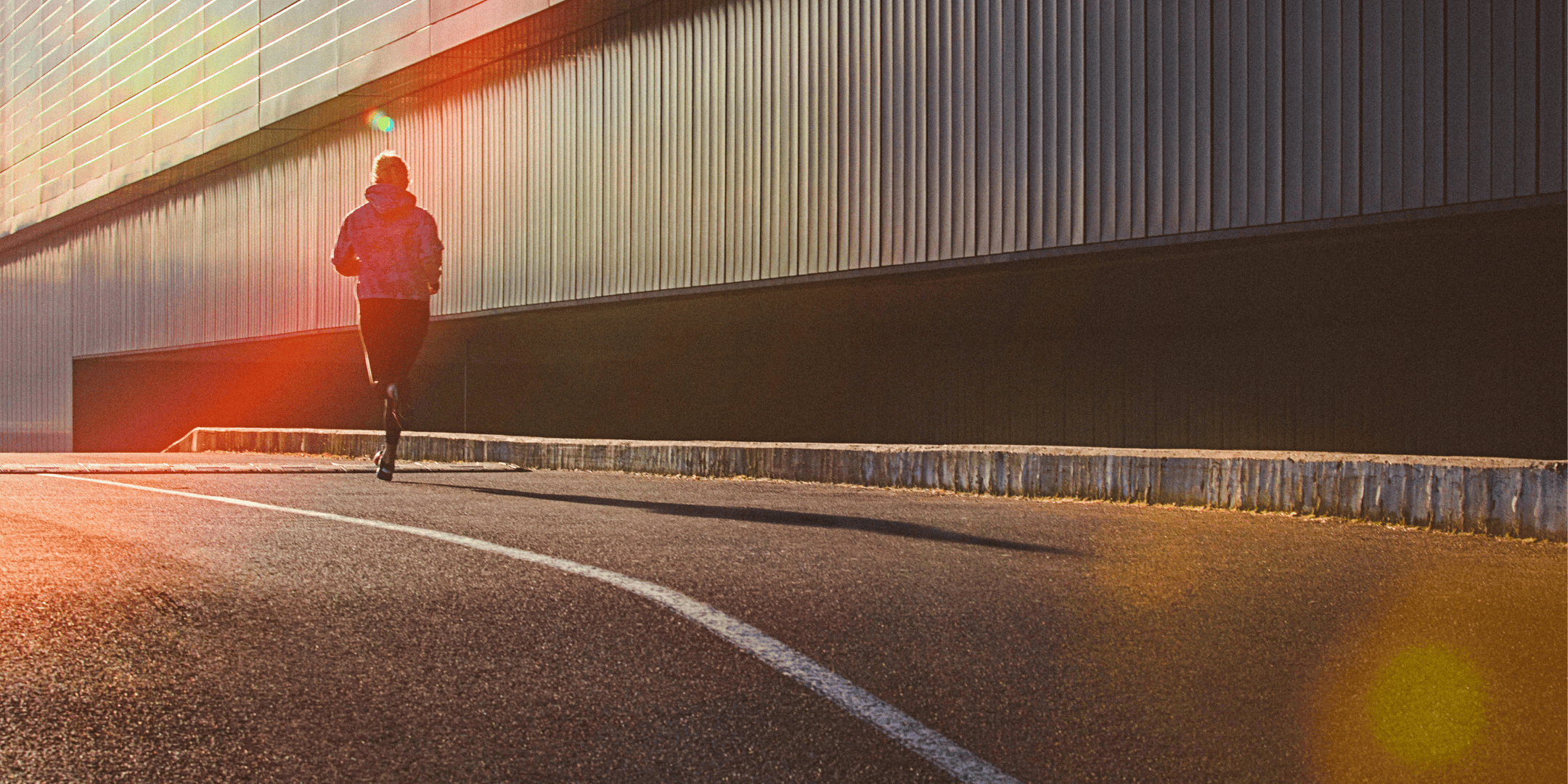 runner on the side of road with lens flare in bottom right hand corner